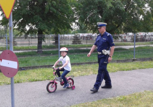 Sprawdzanie praktycznych umiejętności jazdy na rowerze pod okiem policjanta.