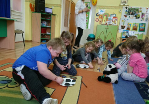 Grupa dzieci układa sylwetę pandy z gotowych elementów.