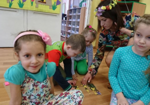 4 dzieci układa obrazek żonkili. Pomaga im nauczycielka z wiankiem kwiatów na głowie.