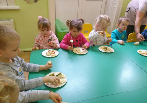 Przedszkolaki nakładają na patyczki szaszłykowe kawałki owoców.