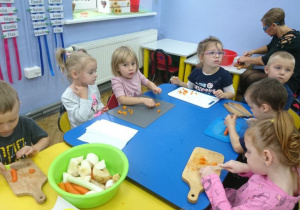 Dzieci kroją gotowaną marchewkę.