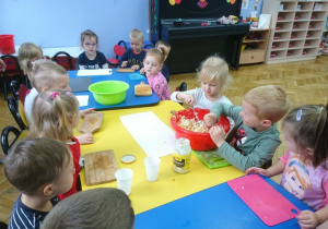 Dzieci doprawiają sałatkę do smaku.