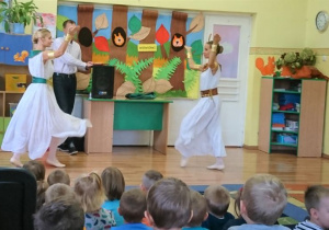 2 tancerki w białych strojach prezentują taniec.