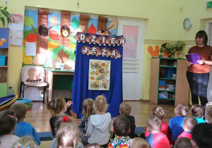 Dzieci słuchają opowiadania o jeżykach czytanego przez nauczycielkę.