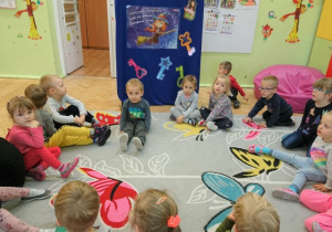 Dzieci siedzą w kole na dywanie.