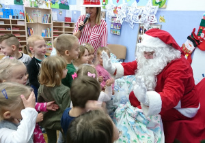 Mikołaj pokazuje dzieciom prezenty.