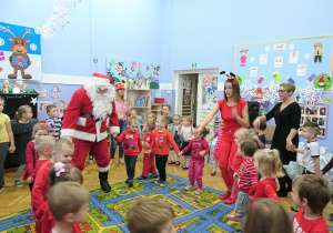 Mikołaj tańczy z dziećmi w kole.