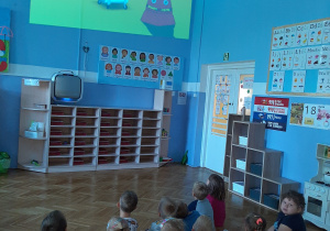 Dzieci oglądają wyświetlany za pomocą rzutnika film edukacyjny.