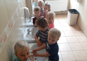Przedszkolaki myją ręce w łazience.