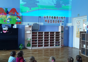 Grupa dzieci ogląda wyświetlane za pomocą rzutnika krajobrazy Polski.