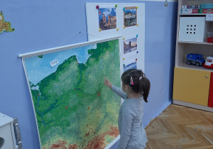 Dziewczynka pokazuje na mapie Polski jeziora.
