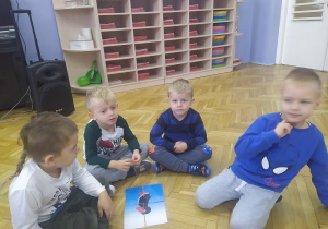 4 chłopców układa sylwetę pingwinka z pociętych elementów.