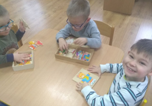 3 chłopców układa drewniane układanki z misiami.