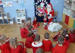 Mikołaj wręcza prezenty dzieciom.