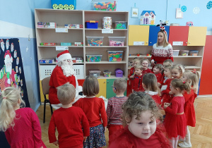 Dzieci stoją wokół Mikołaja i śpiewają piosenkę.