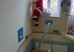 Mikołaj schodzi po drabinie do dzieci.