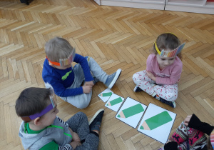 4 dzieci układa według wielkości rysunki zielonej kredki.