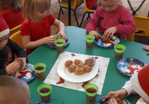 Przedszkolaki ozdabiają pierniczki.