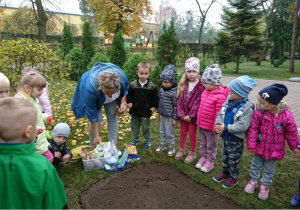 Pani Agnieszka pokazuje dzieciom cebulki kwiatowe.