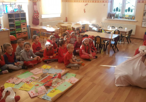 Św. Mikołaj z workiem prezentów rozmawia z dziećmi.