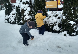 Dzieci bawią się śniegiem w ogrodzie przedszkolnym.