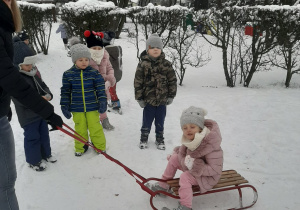 Dziewczynka siedzi na sankach.