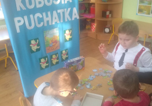 Dzieci układają puzzle "Kubuś Puchatek".