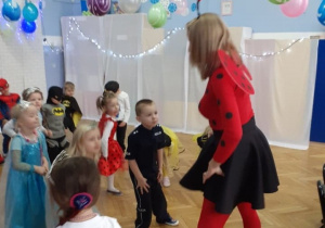 Dzieci naśladują układ taneczny prezentowany przez nauczycielkę.