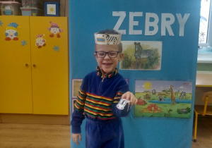Chłopczyk prezentuje przestrzenną figurkę zebry wykonaną z kartonu.