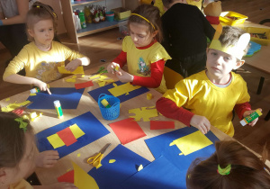 Grupa dzieci klei przy stoliku sylwety Kubusia Puchatka.