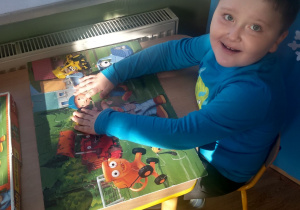 Chłopczyk prezentuje ułożone przez siebie puzzle "Bob Budowniczy".