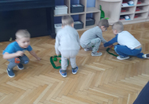 Chłopcy zbierają kuleczki do zielonych szarf rozłożonych w sali.