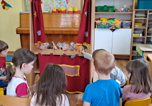 Dzieci bawią się w teatrzyk z wykorzystaniem wykonanych przez siebie zwierzątek i kurtyny teatralnej.