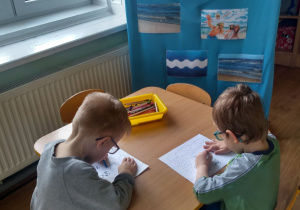 Dwóch chłopców koloruje ilustrację kropel wody.