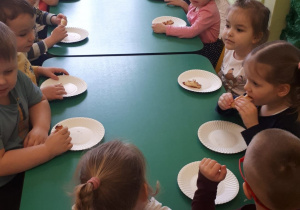 Dzieci spożywają świeżo upieczone rogaliki.