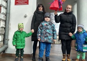 Dzieci i panie stoją przed budynkiem przedszkola.