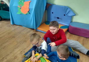 3 chłopców sznuruje sylwetkę ślimaka na kostce manipulacyjnej.