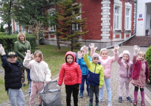 Grupa "Słoneczek" na tle budynku przedszkolnego gotowa do sprzątania świata.a