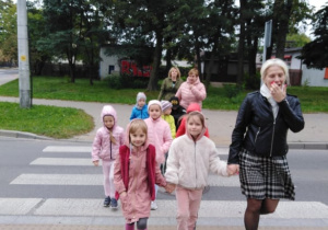 Dzieci z opiekunem przechodzą przez przejście dla pieszych.