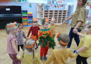Dzieci tańczyły w kole trzymając się za ręce. W środku jedno dziecko trzyma bukiet jesiennych liści