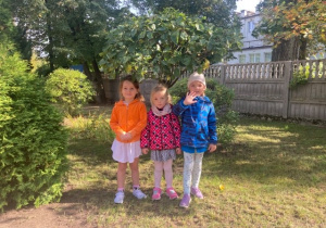Trzy dziewczynki schroniły się pod drzewkiem.