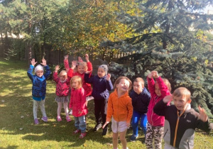 Dzieci radośnie machają rękami, ciesząc się z pięknej pogody.