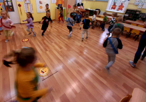 Dzieci poruszają się po sali przedszkolnej w rytmie tamburyna.