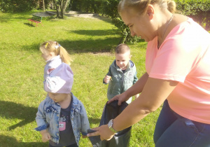 Dzieci z grupy Wiewiórki uczą się jak dbać o czystość w ogrodzie przedszkolnym.