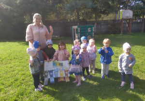 Przedszkolaki podczas wspólnego zdjęcia z plakatem w ogrodzie przedszkolnym.