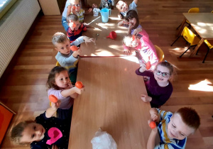Dzieci mieszają mąkę z wodą w zawiązanych balonach poprzez ugniatanie ich palcami dłoni.
