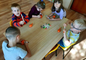 Dzieci siedzą przy stolikach. Rysują mazakami na swoich „Gniotkach” oczy, nos i usta. Z pomocą nauczyciela przywiązują włosy z włóczki.