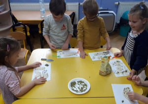 Dzieci dekorują ziarnami uformowane pieczywa