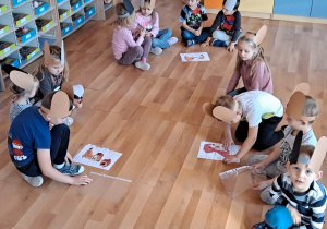 Trzy zespoły dzieci układają obrazek psa z części na podłodze.