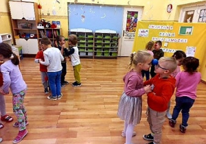 Dzieci tańczą w parach, trzymając małą piłeczkę czołami.